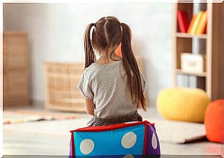 Little girl sitting back to back above an inflatable cube.