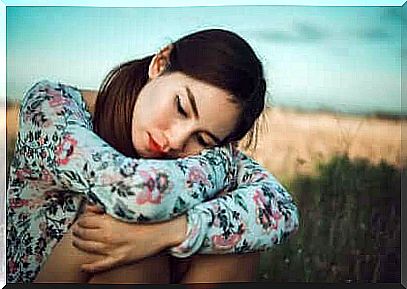 Girl with legs gathered in a meadow.