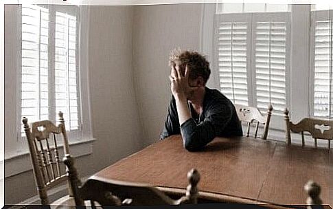 Exhausted boy leaning against a table.