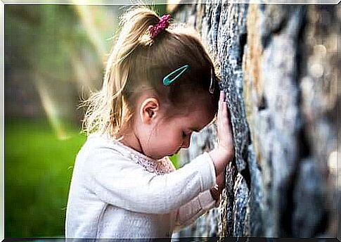 Sad little girl leaning against a wall