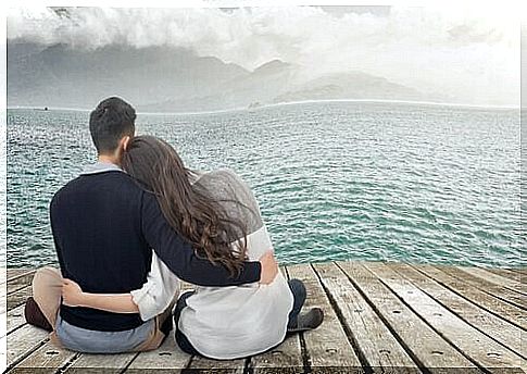 Couple embraced on the pier in front of the sea