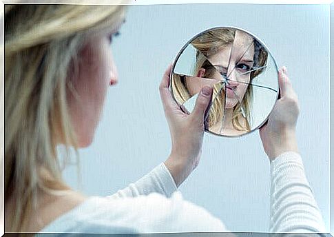 Girl-looking-at-her-reflection-in-a-broken-mirror