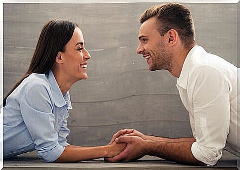 Couple talking holding hands lying on the ground