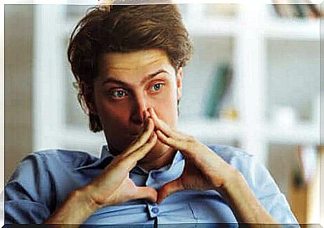 Pensive boy with hands in front of his face.