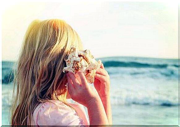 Woman listening to the sound of the sea in the shell