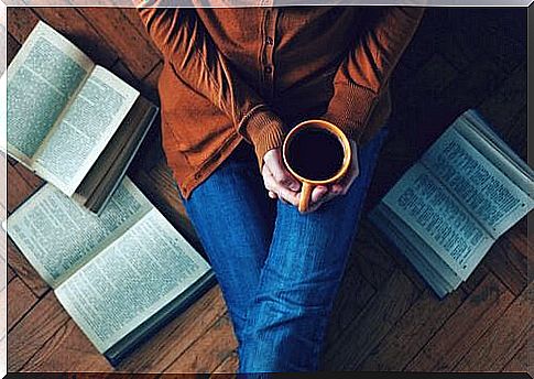 woman-drinks-coffee-sitting-on-the-ground-with-books